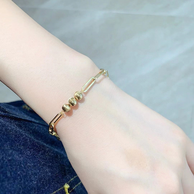 Gold bracelet on a wrist with a neutral background