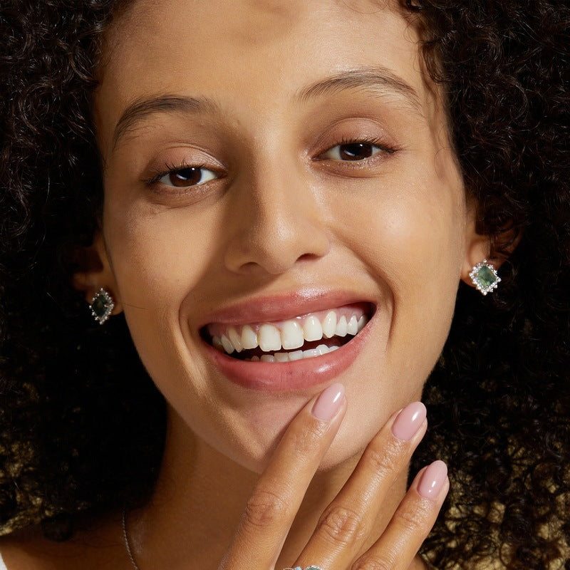 Close-up of a woman wearing green gemstone earrings with a blurred background