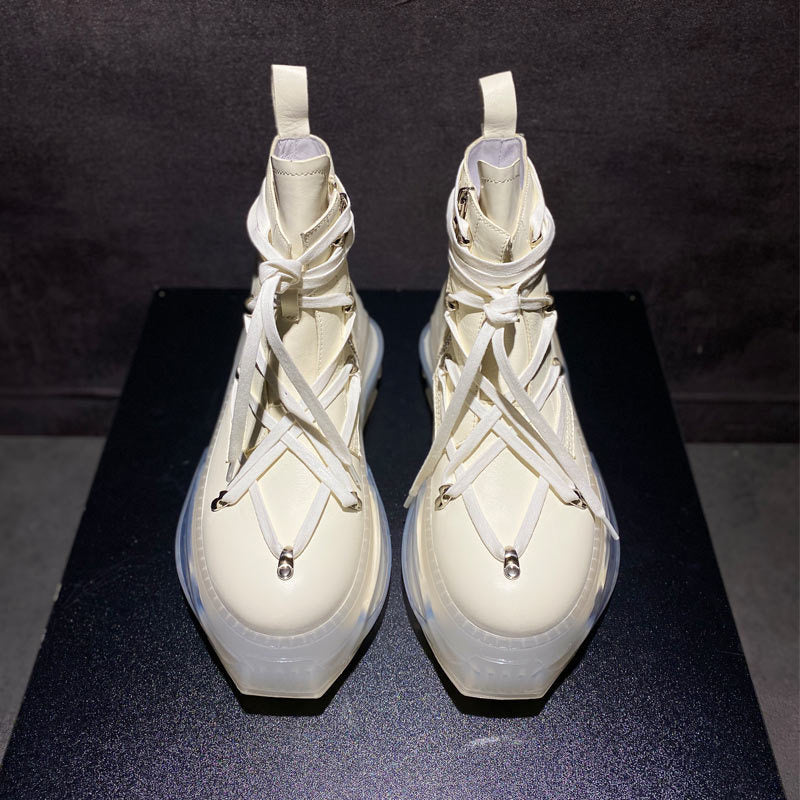 Pair of white high-top sneakers with unique design on a dark surface