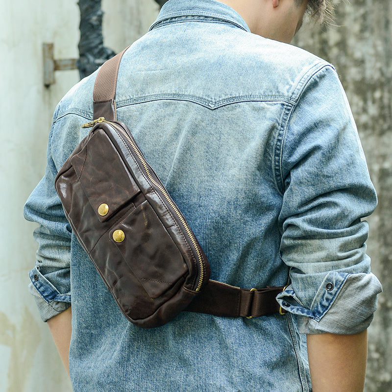 Person wearing a brown leather waist bag over a denim jacket.