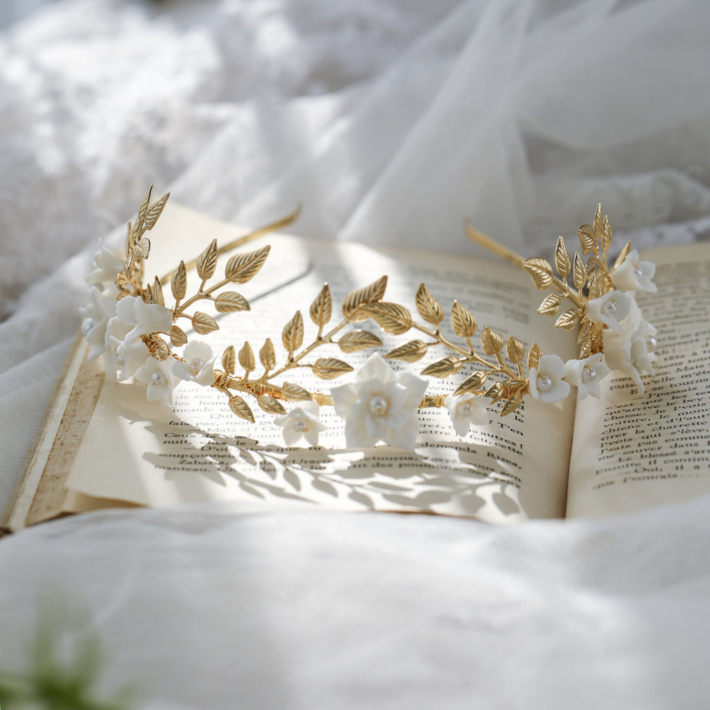 Gold and white floral headbands on an open book with a soft white background