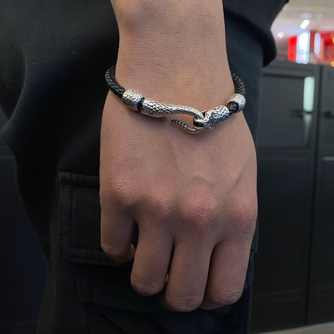 Hand wearing a silver bracelet with a dragon design against a blurred background