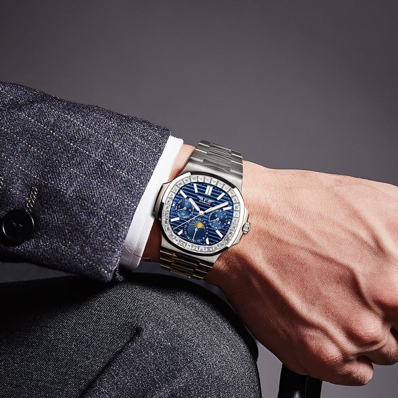 Close-up of a person wearing a silver watch with a blue face on a gray background
