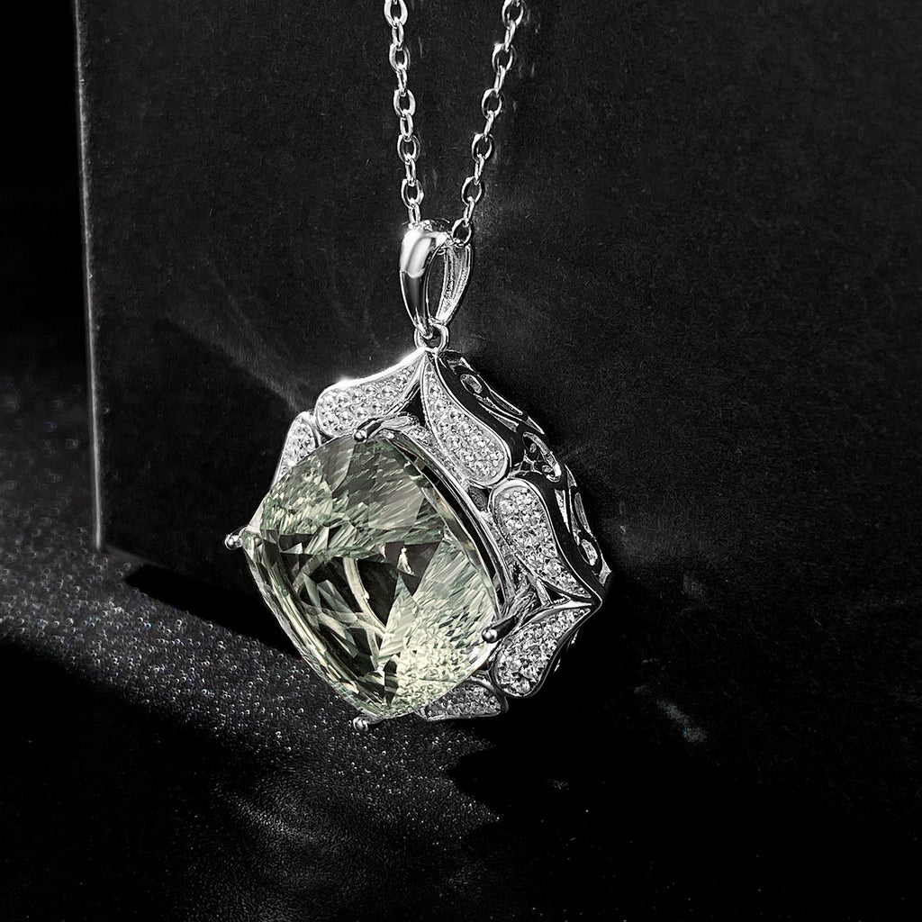 Silver pendant with a green gemstone on a black background