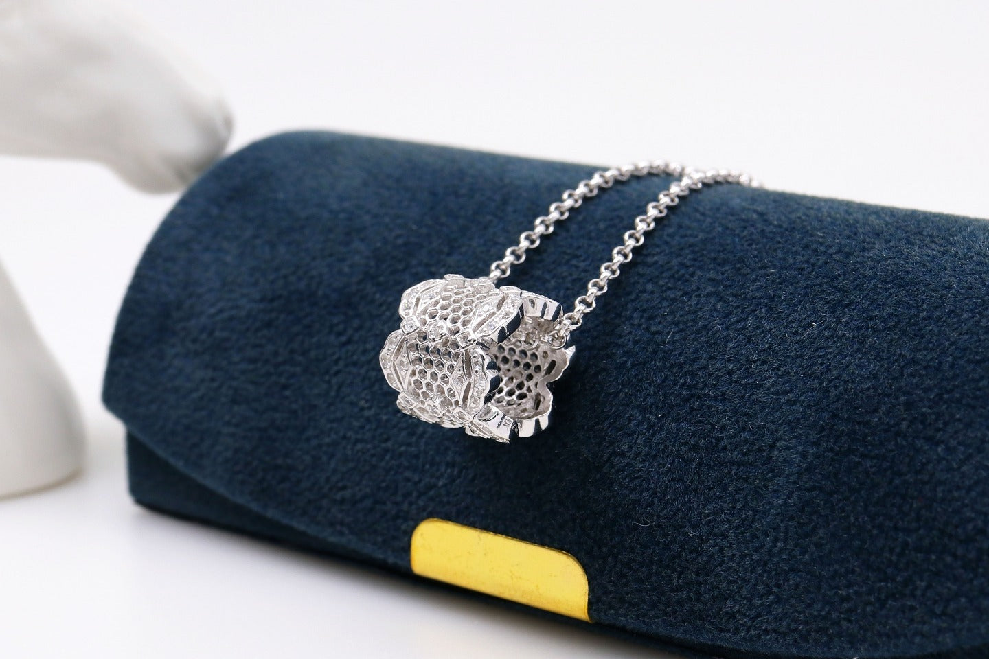 Silver necklace with a unique design on a blue cushion with a yellow tag.
