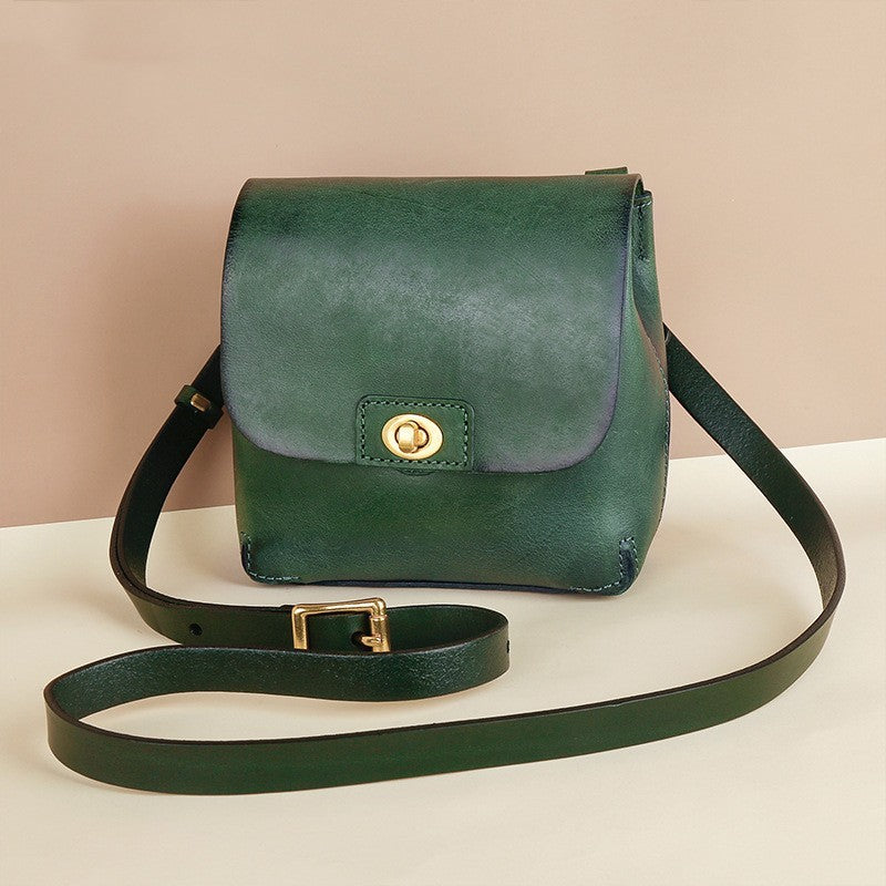 Green leather handbag with a strap on a beige background