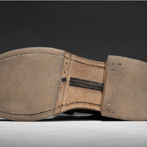 Close-up of a brown leather belt with visible stitching on a dark background