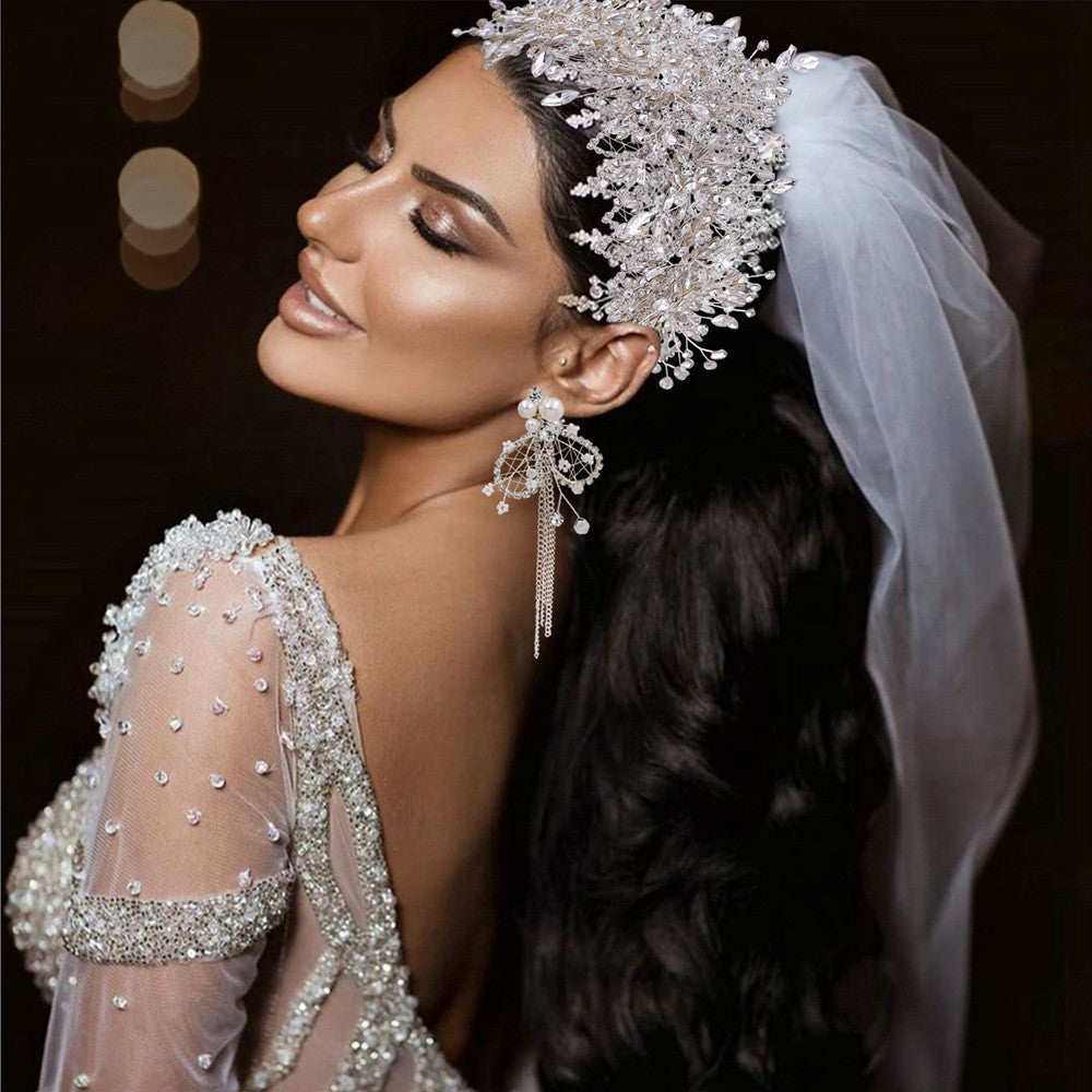 Woman in a wedding dress with intricate jewelry and veil against a dark background