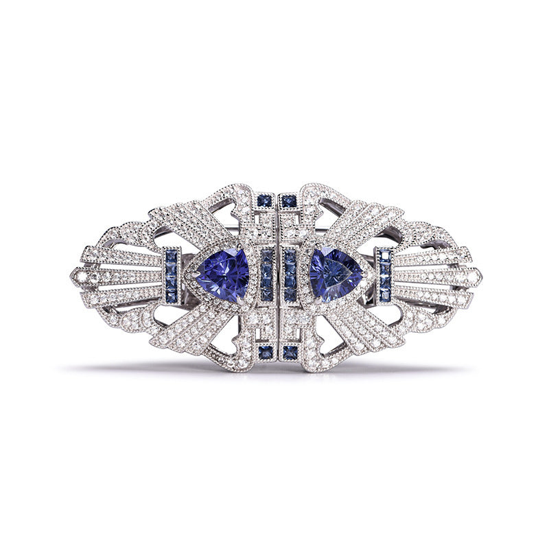 Elegant brooch with blue gemstones and silver detailing on a white background