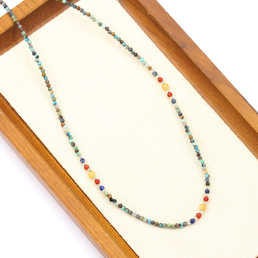 Multicolored beaded necklace on a wooden display box with a white background