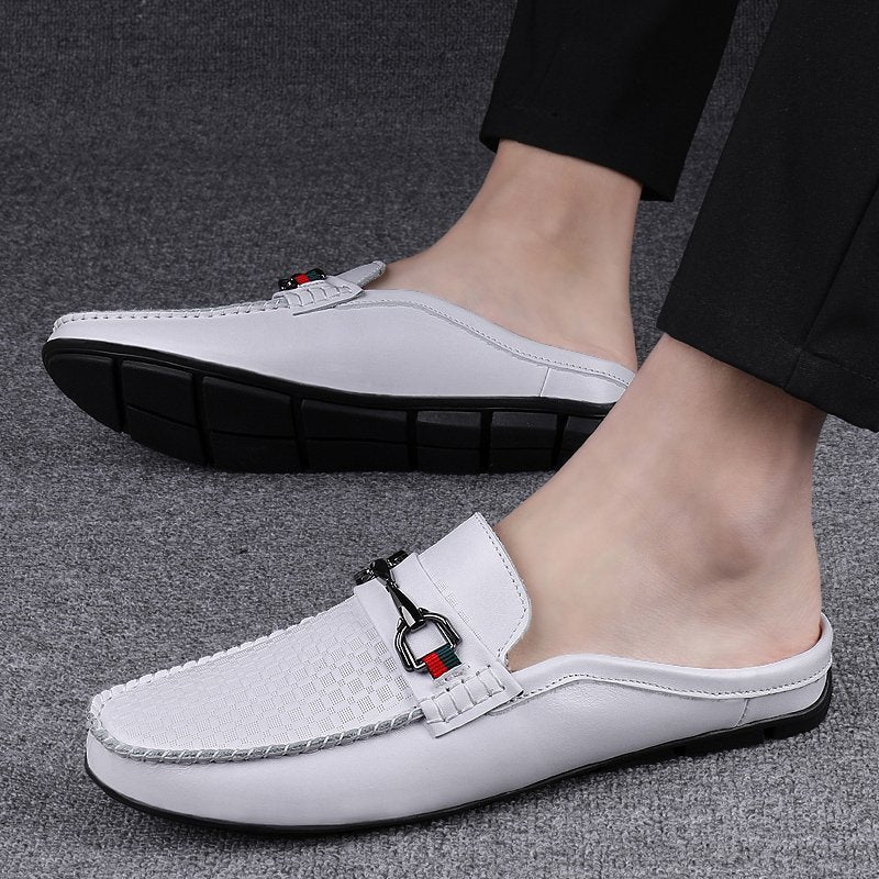 White slip-on shoes with a small decorative tag worn by a person on a gray background