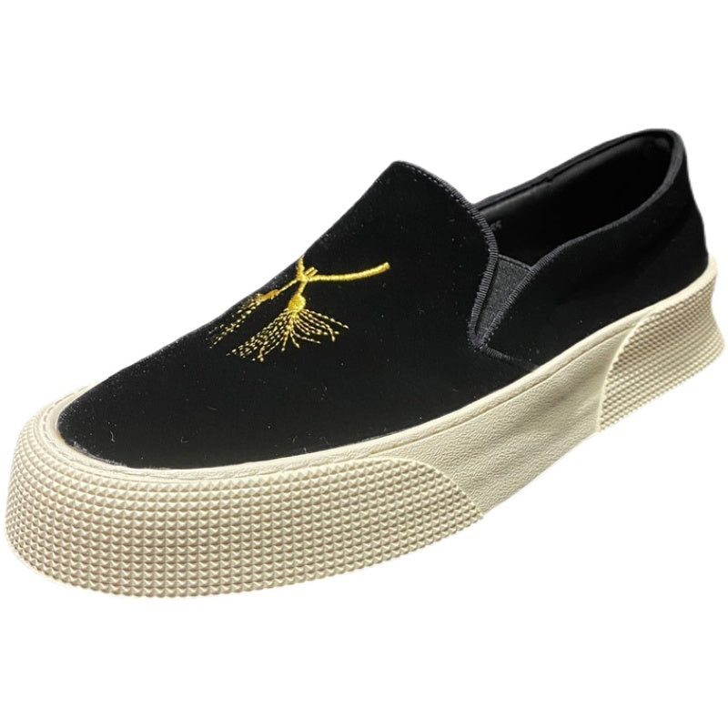 Black slip-on shoe with yellow embroidery on a white background