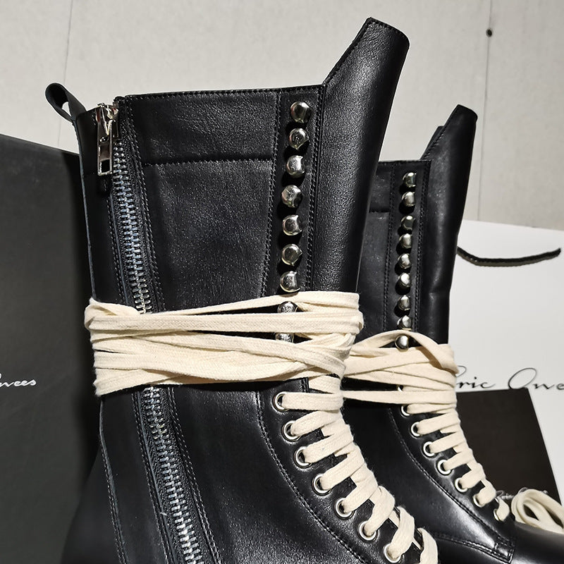 Black leather boot with studded details and white laces on a brand box background