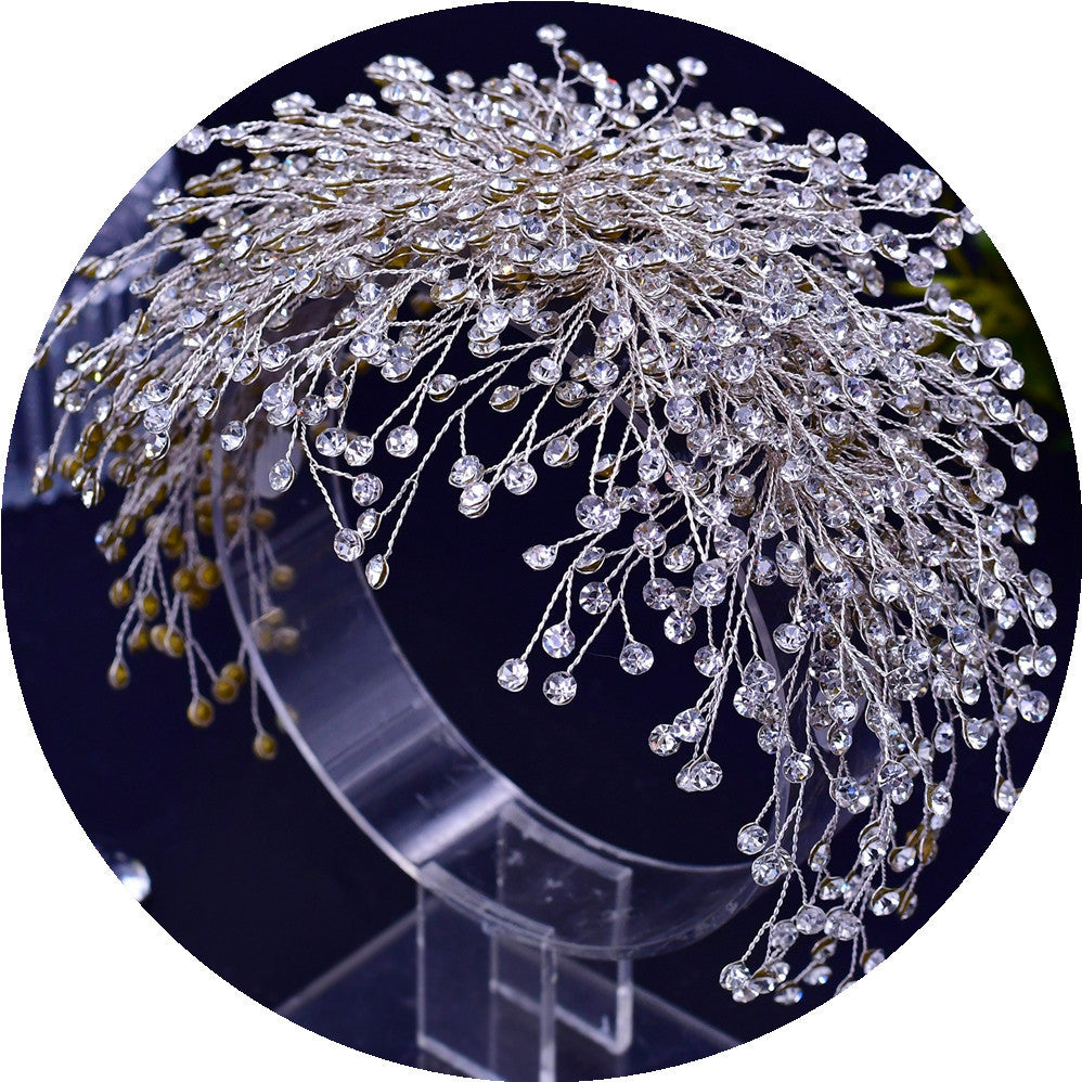 Decorative headpiece with crystals on a clear stand against a dark background