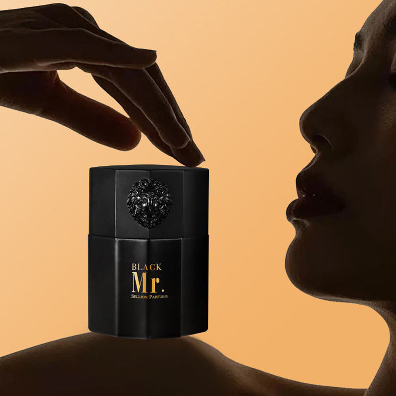 Black 'BLACK Mr.' perfume bottle with a hand about to apply perfume to a woman's neck against an orange background.