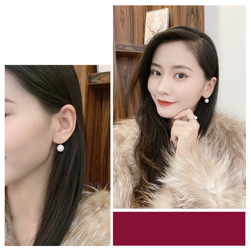 Close-up of earrings worn by a person and a woman wearing them indoors.