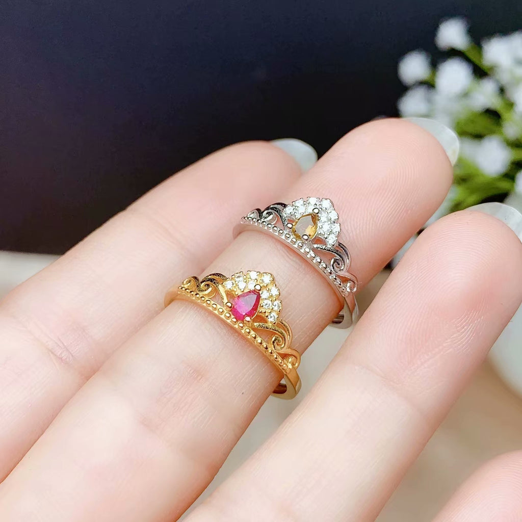 Two tiara-shaped rings on a finger with a blurred background