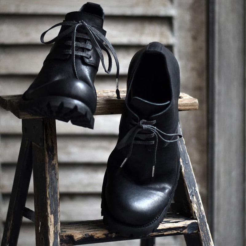 Pair of black leather shoes on a wooden stool with a blurred background