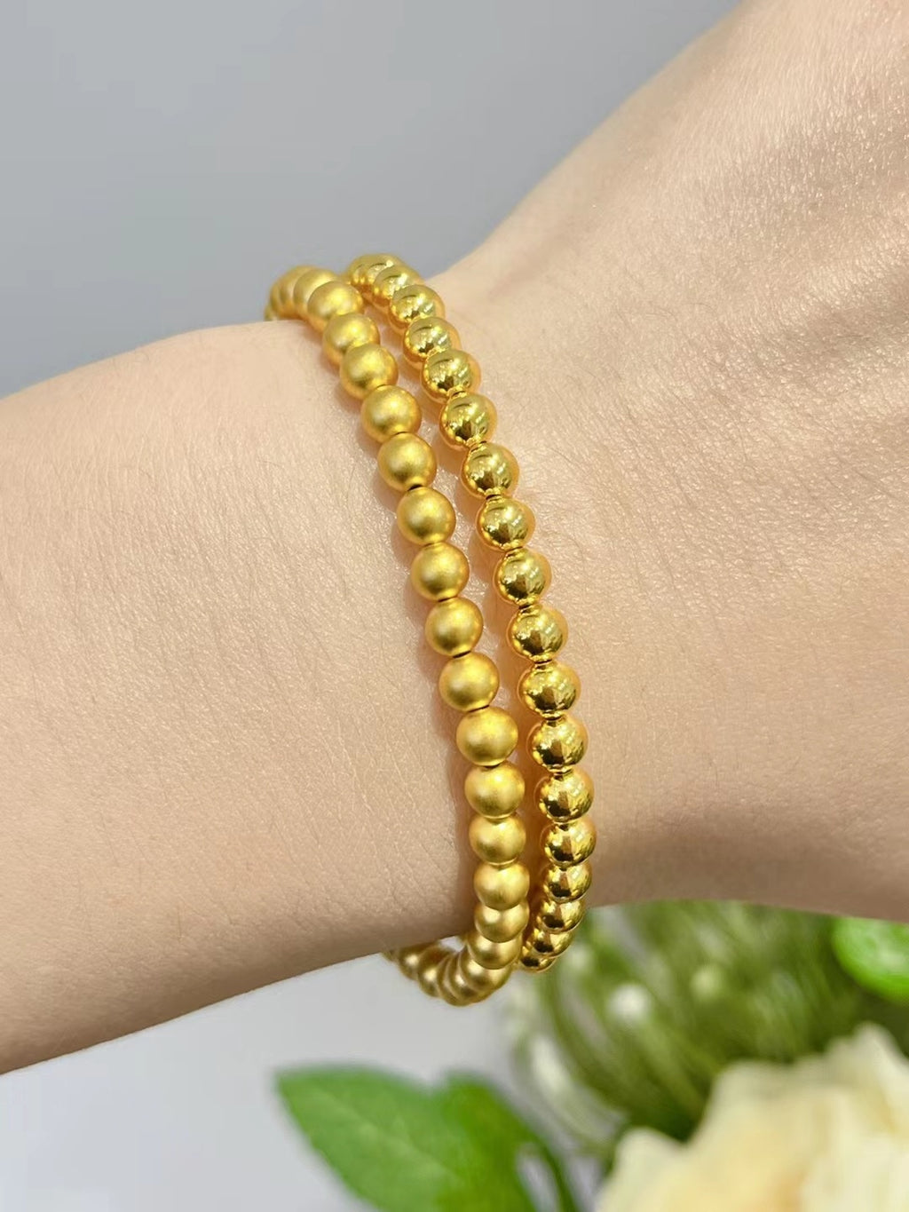 Gold beaded bracelet on a wrist with a blurred background