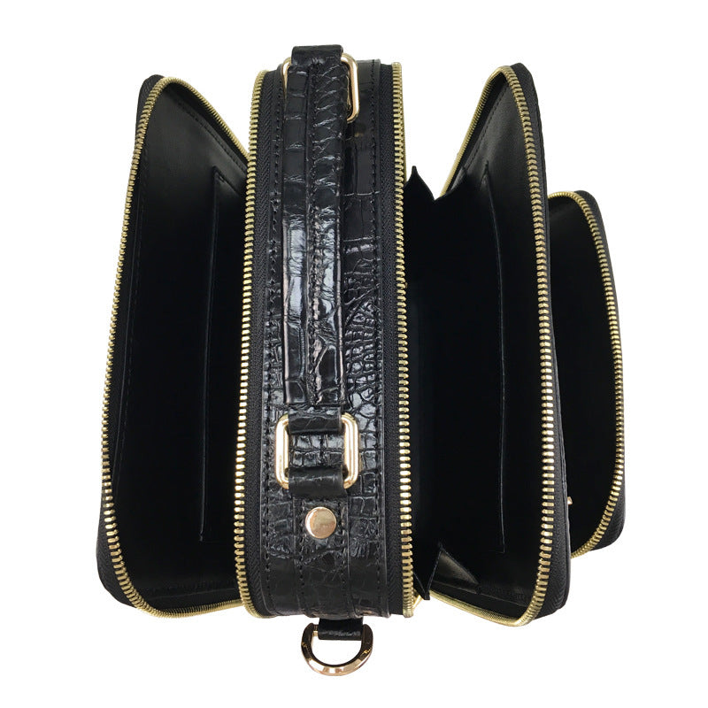Black crocodile skin clutch bag with gold zipper and hardware on a white background