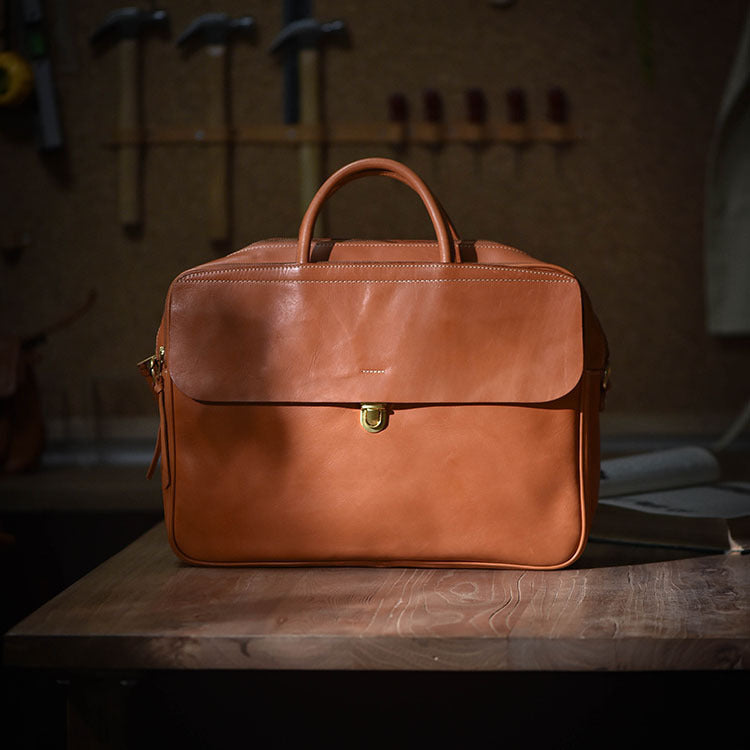 Brown leather briefcase on a wooden surface with tools in the background