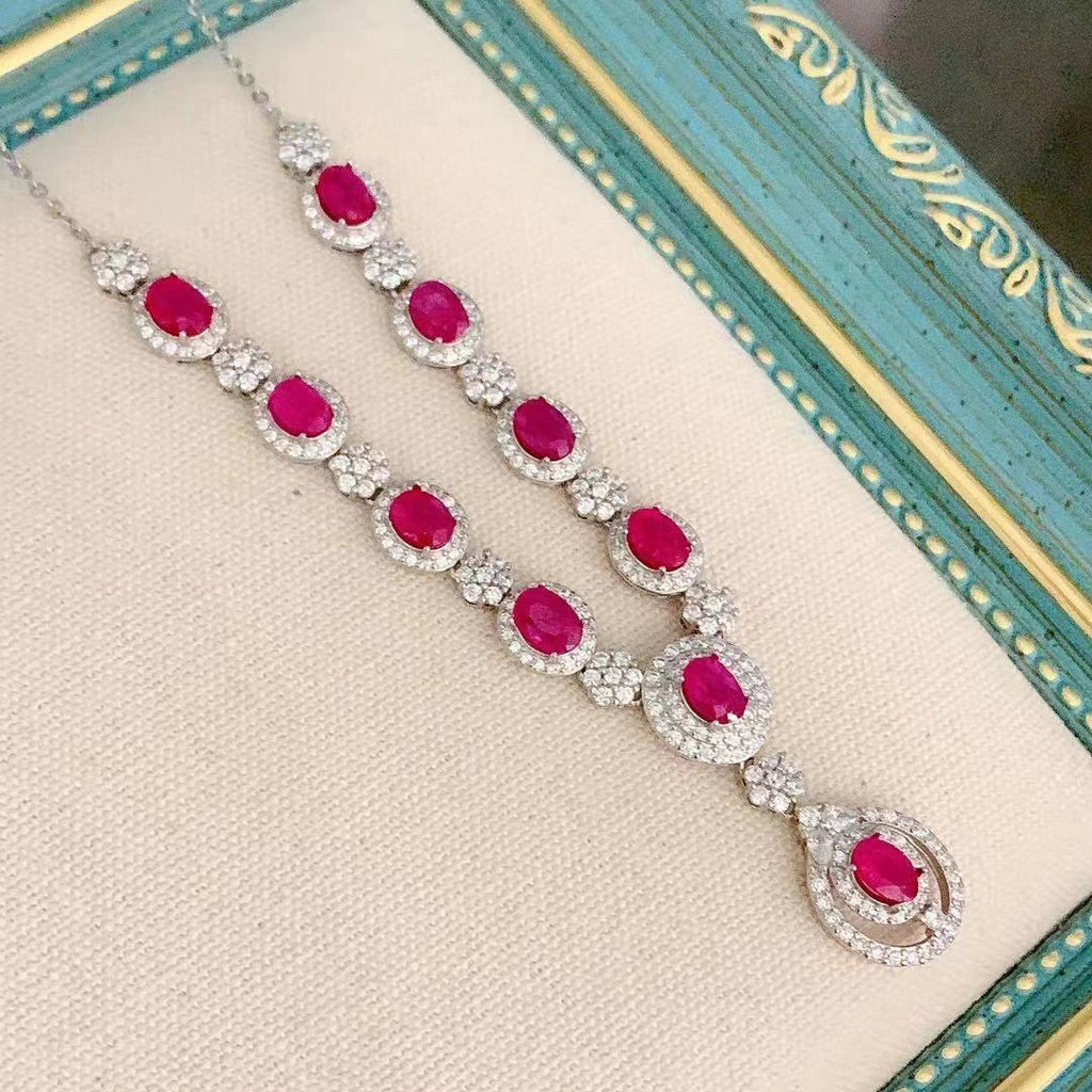 Jewelry set with red gemstones and silver accents on a decorative box