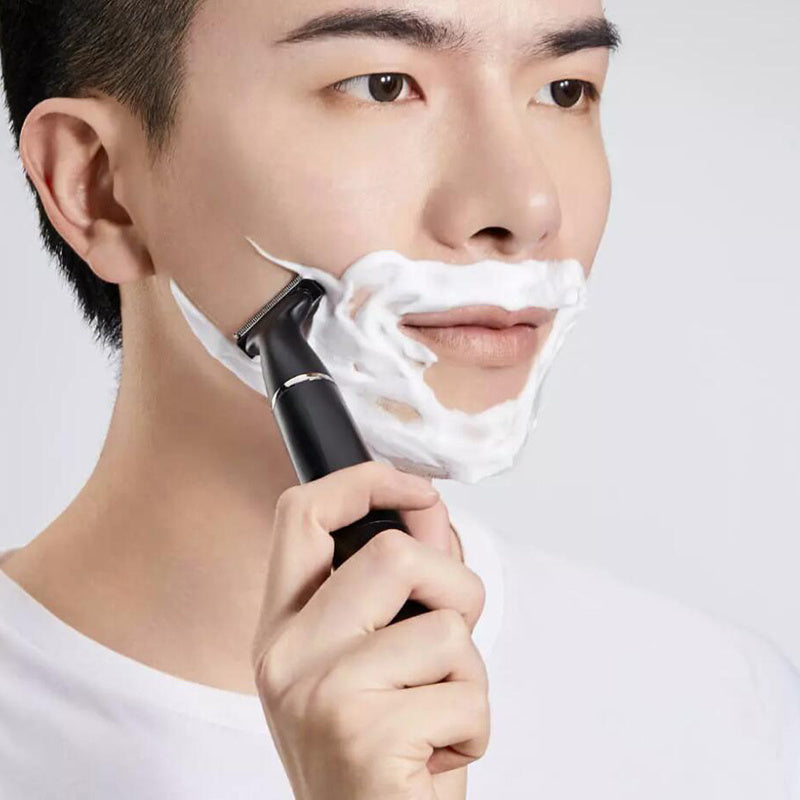 Man using a razor with shaving cream on a white background