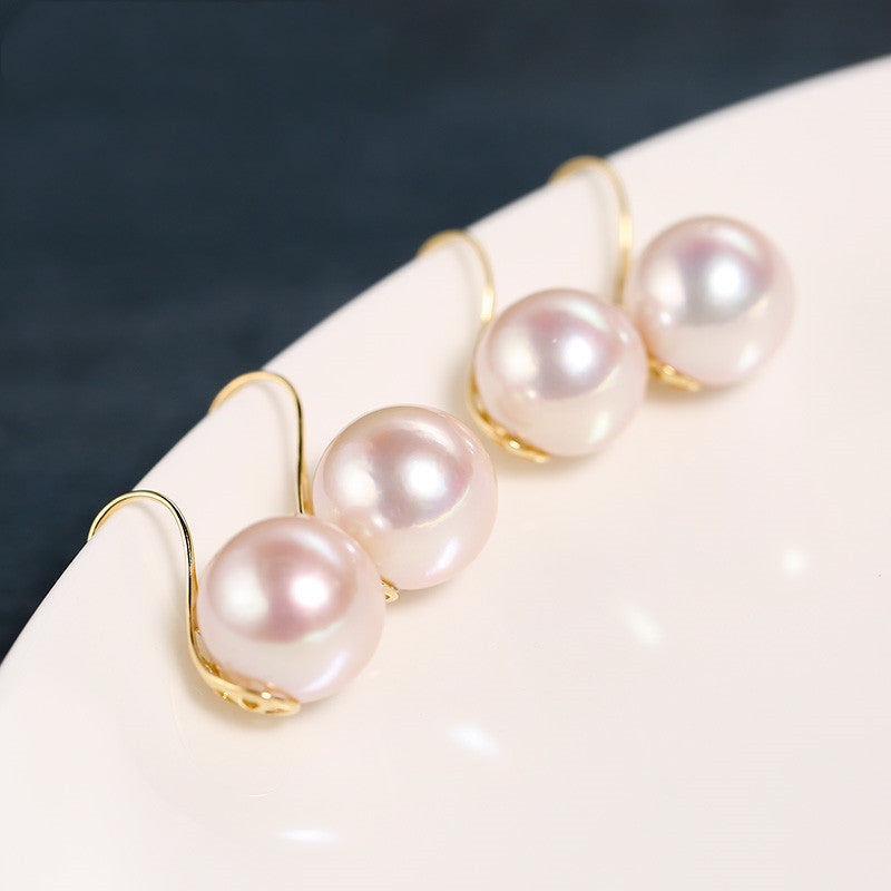 Pearl earrings with gold clasps on a white surface