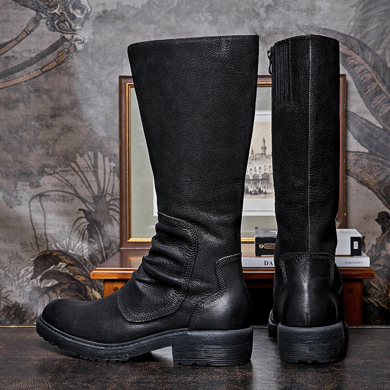 Pair of black leather knee-high boots on a textured surface with a decorative background.
