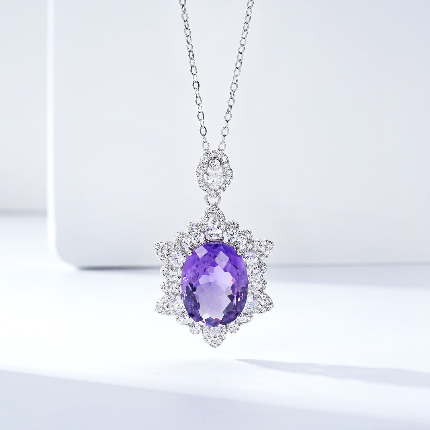 Purple gemstone pendant on a chain against a light background
