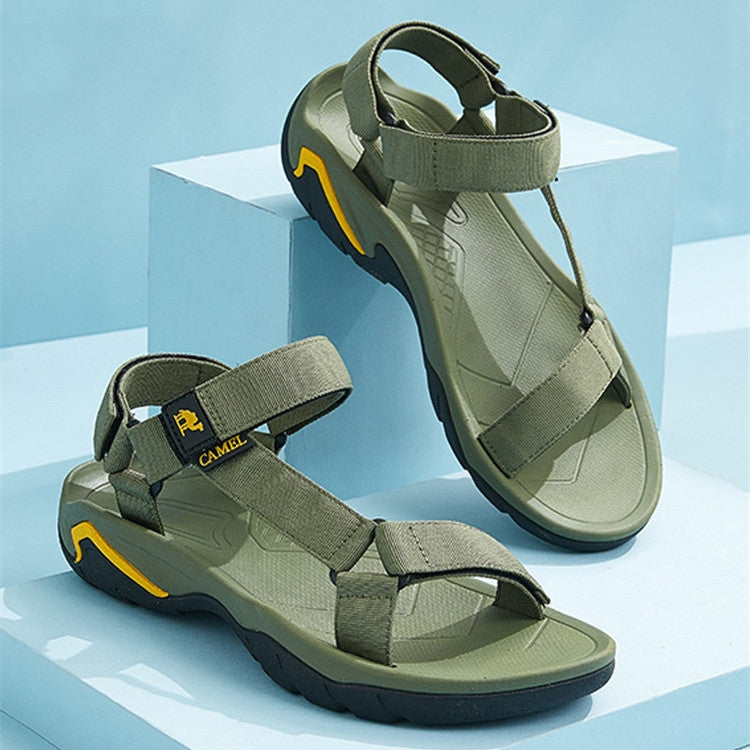 Pair of green sandals with black soles on a light blue background