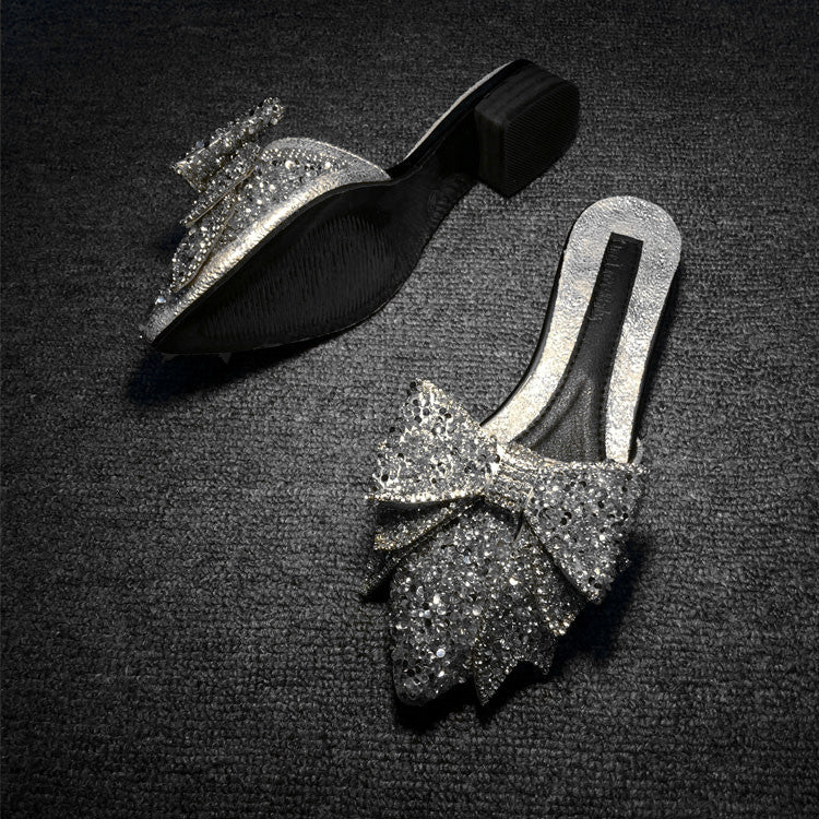 Silver glittery shoes with bow design on a dark textured background