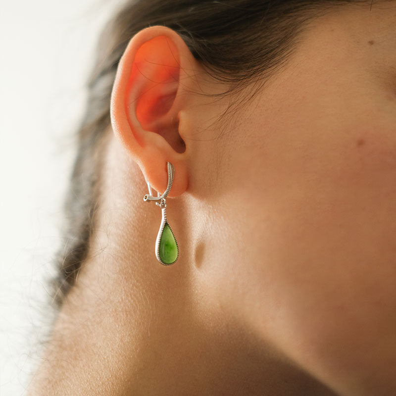 Close-up of a person wearing a green teardrop earring.