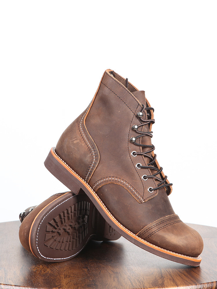 Brown leather boots on a wooden surface with a white background