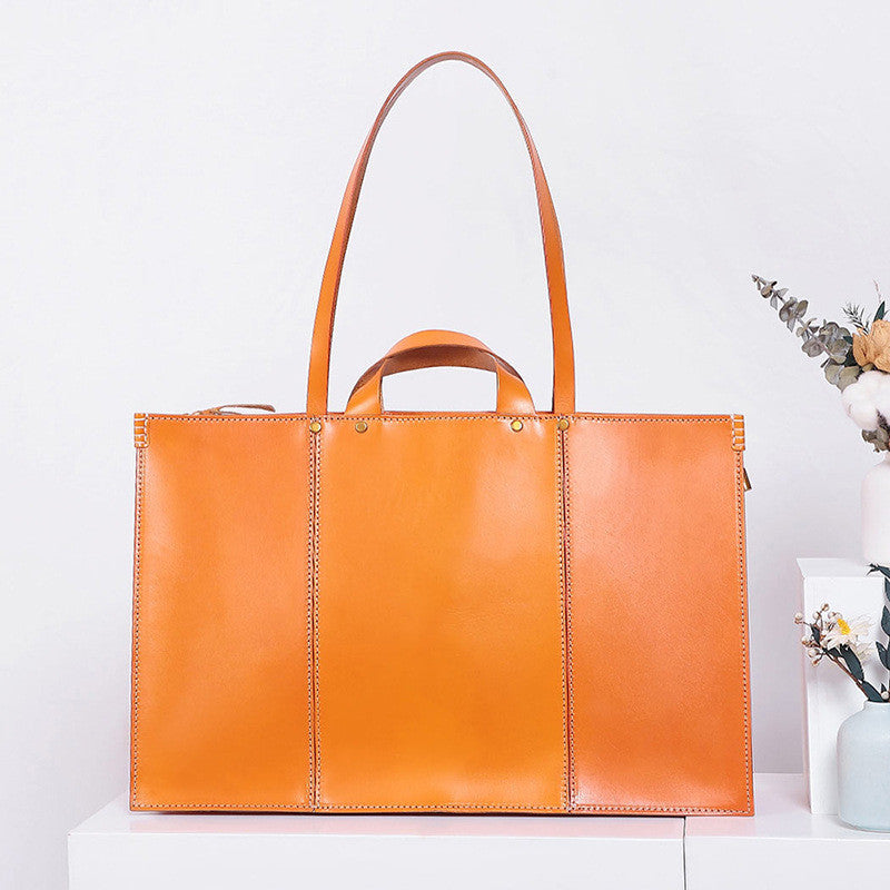 Orange leather tote bag on a white surface with a minimal background