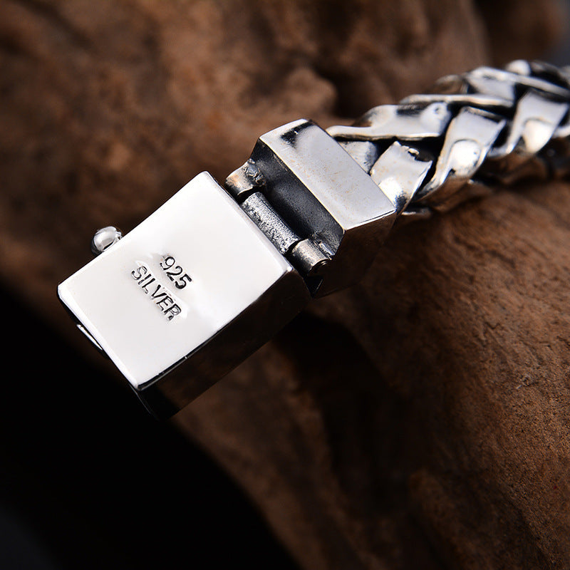 Close-up of a silver bracelet with '925 Silver' engraving on a brown textured background