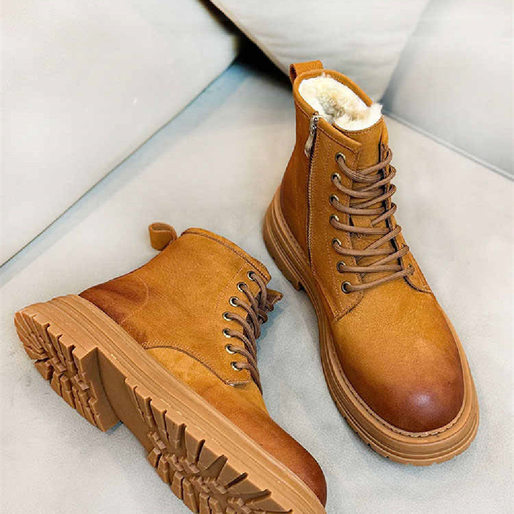 Pair of brown leather boots with white fur lining on a light gray background