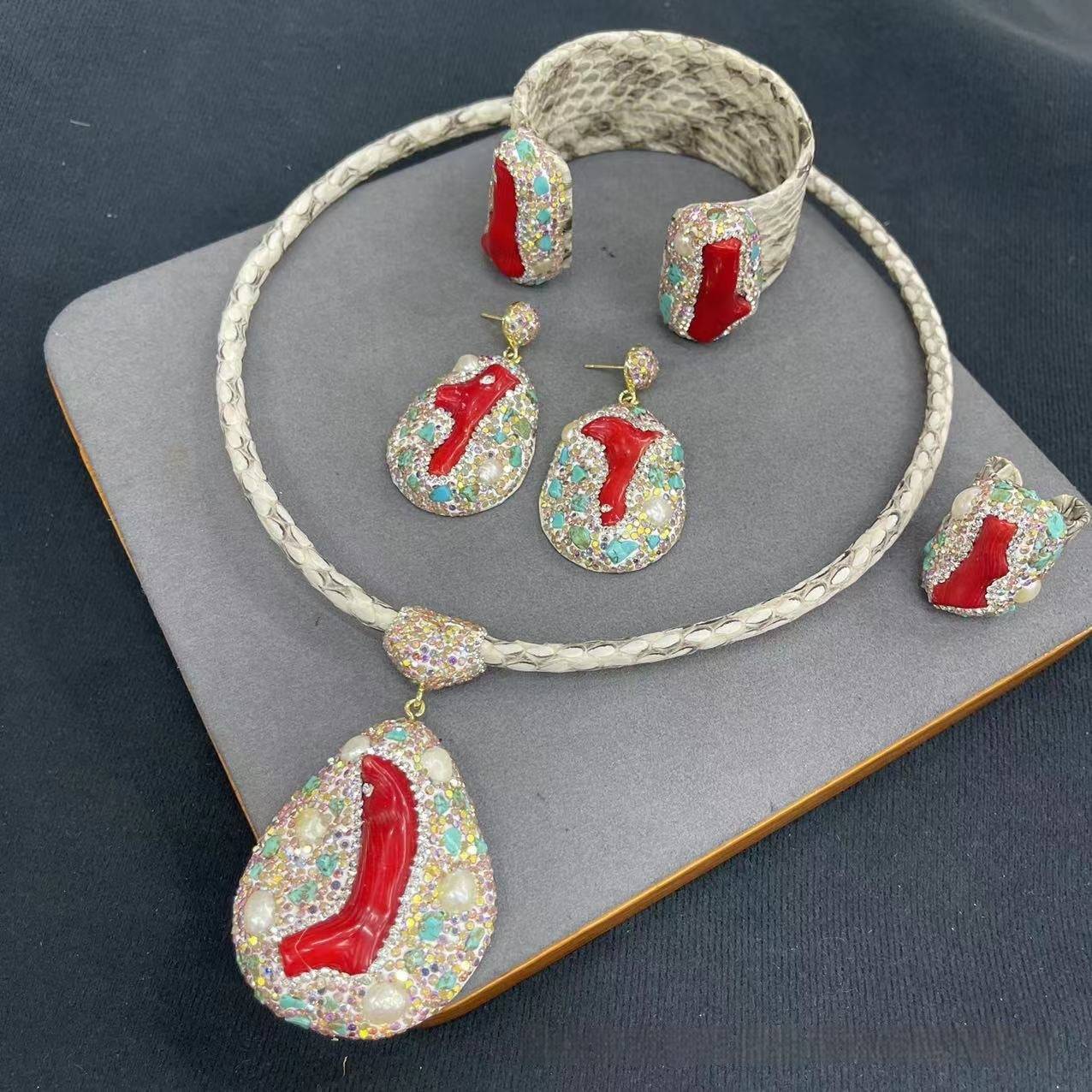 Jewelry set with red and multicolored stones on a dark surface