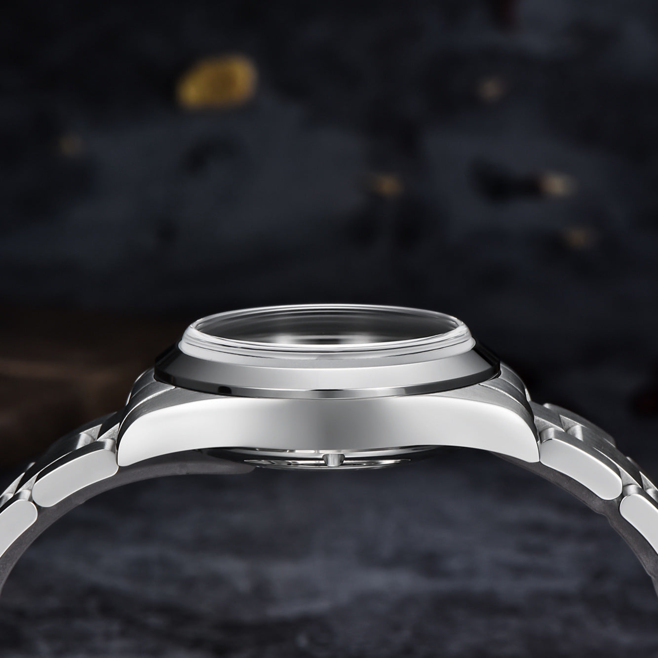 Close-up of a silver watch case on a dark textured background