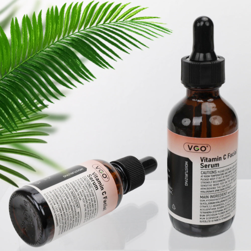 Two VCO Vitamin C Facial Serum bottles with a fern leaf on a light background