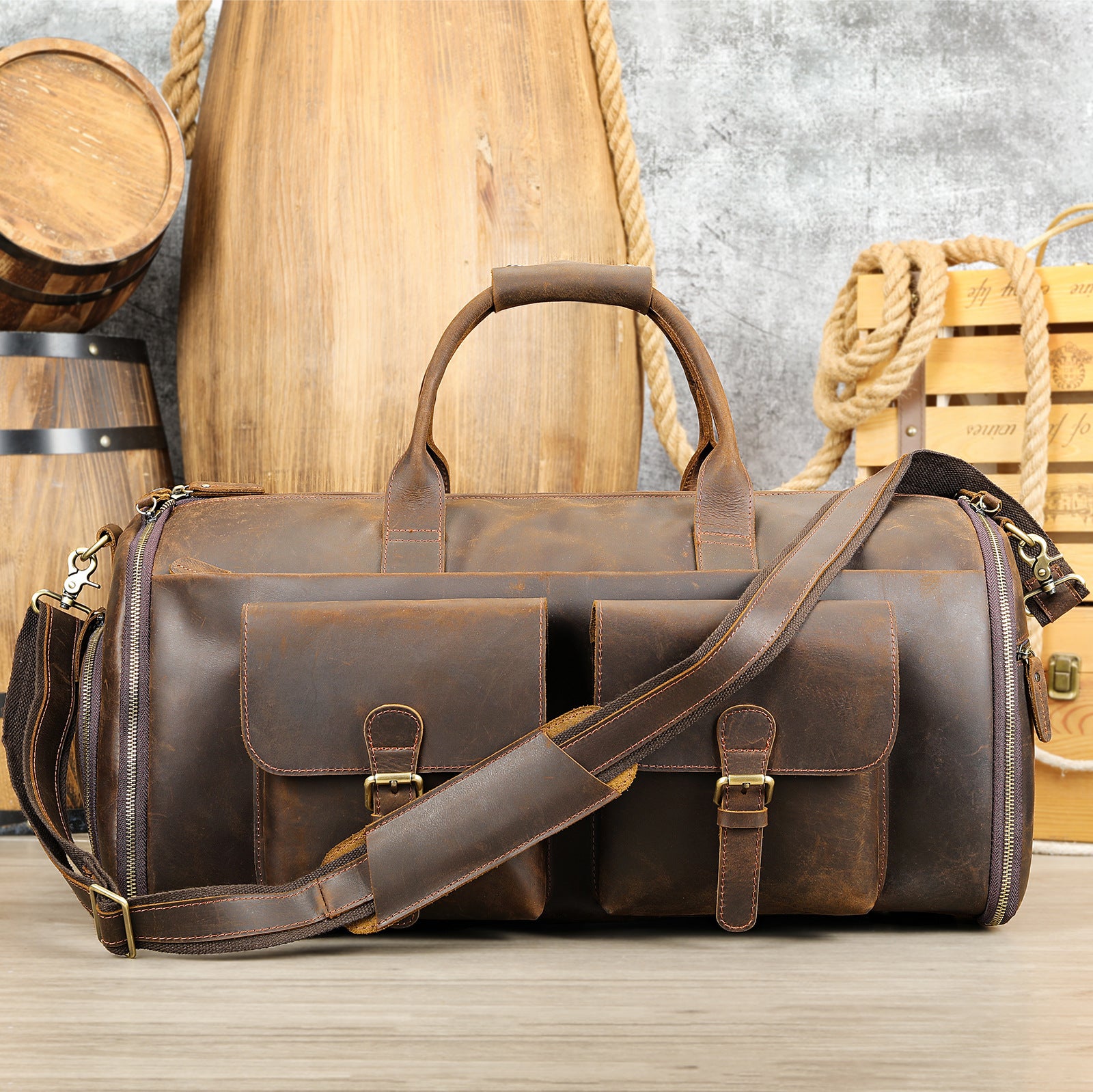 Brown leather duffel bag with shoulder strap on a wooden surface with rustic background