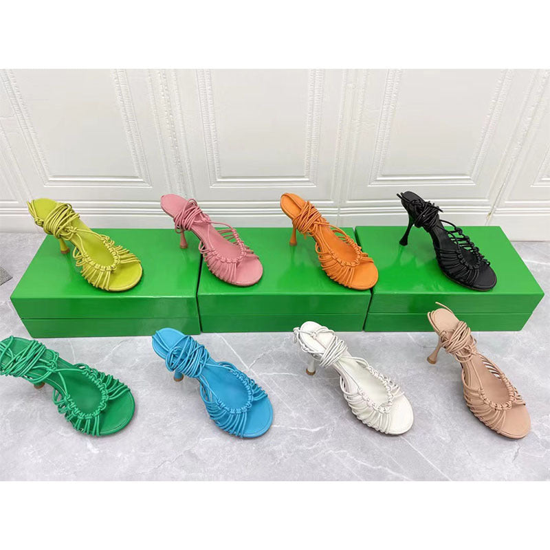 Colorful high-heeled shoes displayed on a green platform against a white paneled wall.