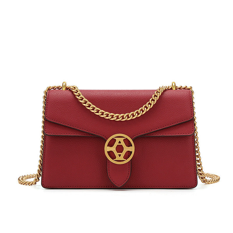 Red handbag with gold chain and emblem on a white background