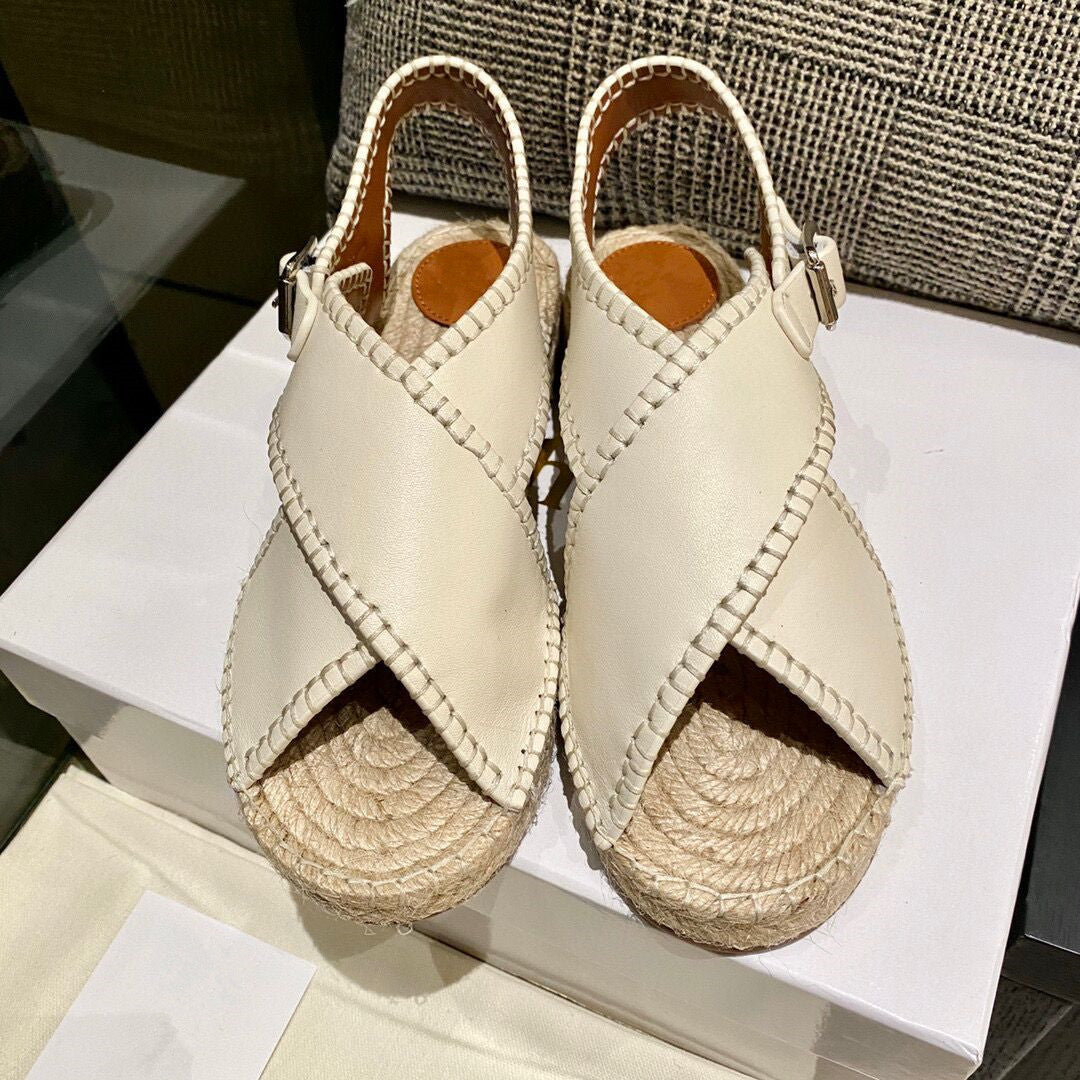 Pair of beige sandals with woven soles on a white surface.