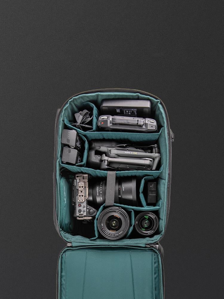 Teal camera bag with compartments containing camera equipment on a dark background