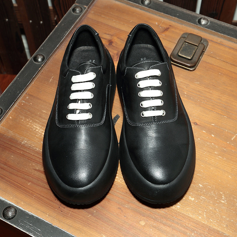 Pair of black leather shoes with white laces on a wooden surface