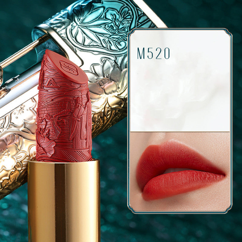 Red lipstick with gold cap and decorative case, displayed with a smartphone showing lipstick color on screen.