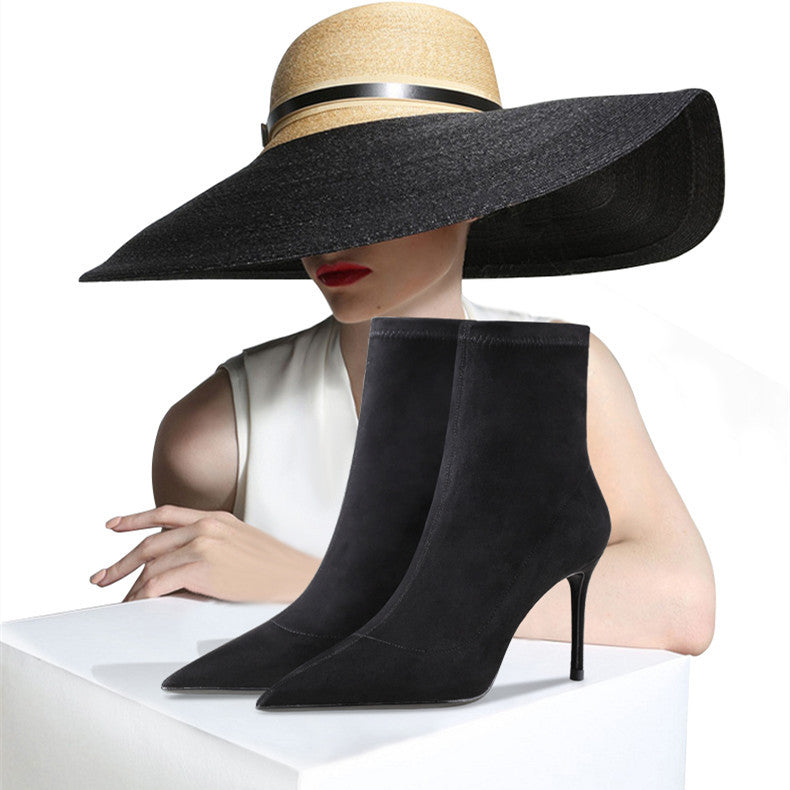 Black high-heeled boots with a person wearing a large black hat on a white background
