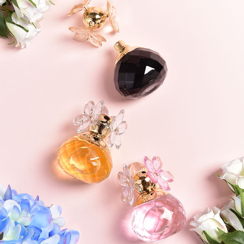 Three perfume bottles with floral designs on a pink background