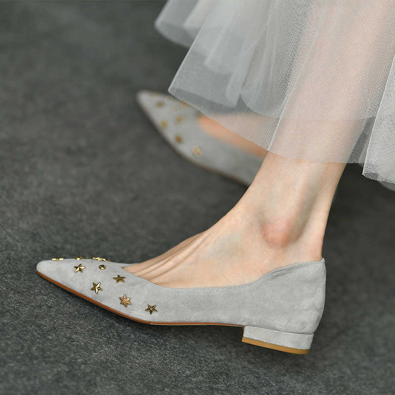 Gray suede shoes with star embellishments worn by a person on a dark surface